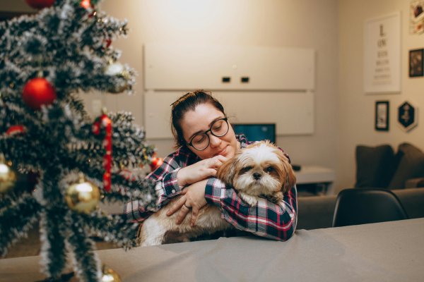 Majitelka uklidňuje svého psa u vánočního stromku